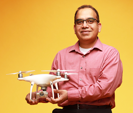 Asheesh Singh holds a drone in front of gold background