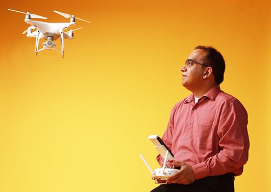 Asheesh Singh flys a drone in front of gold background